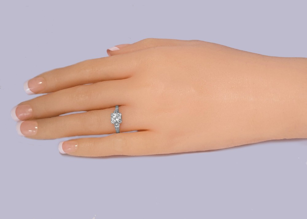 A platinum solitaire ring featuring a central round brilliant diamond held in a claw setting with stepped diamond shoulders. View XI