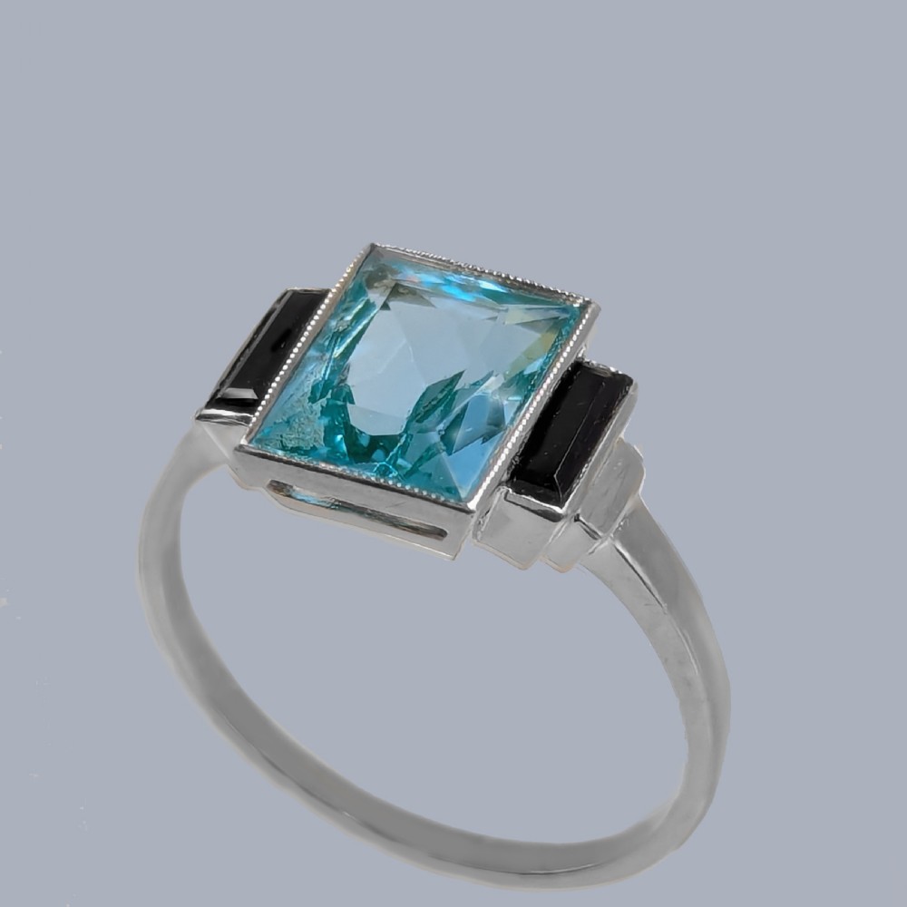 An 18ct white gold Art Deco ring featuring a central rectangular light blue spinel stone flanked by two vertical black onyx baguettes with millegrain borders. View III