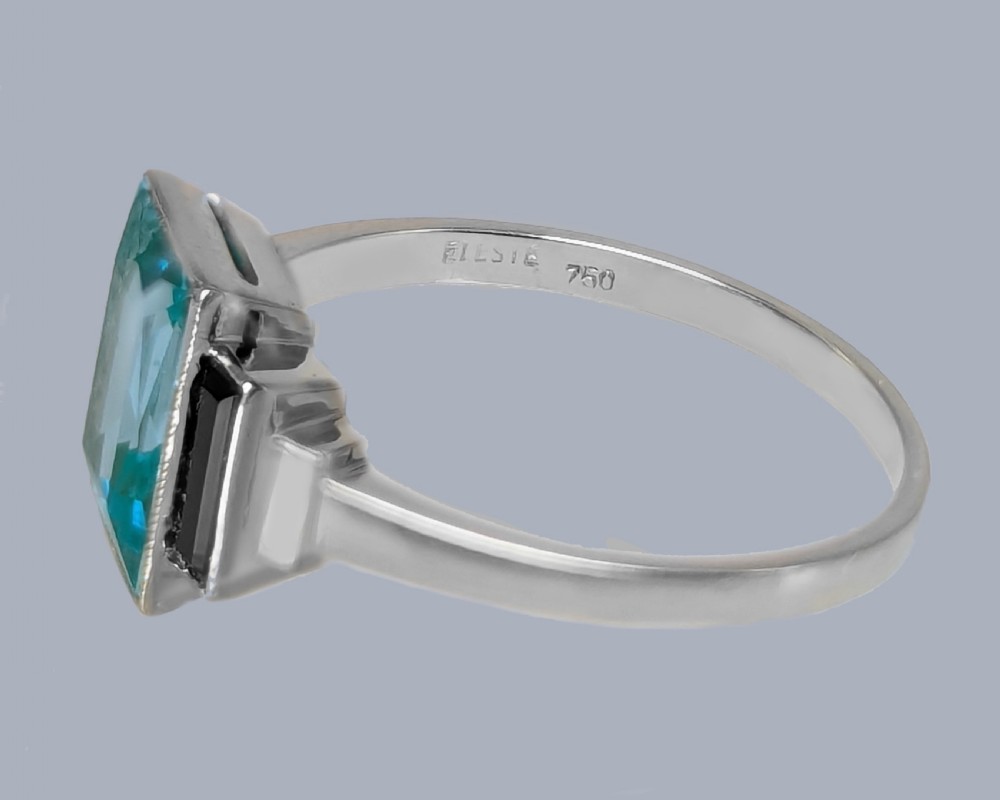 An 18ct white gold Art Deco ring featuring a central rectangular light blue spinel stone flanked by two vertical black onyx baguettes with millegrain borders. View IX