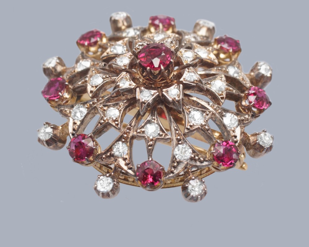 A circular Victorian starburst brooch featuring central and outer natural rubies surrounded by openwork diamond-set filigree. View IV