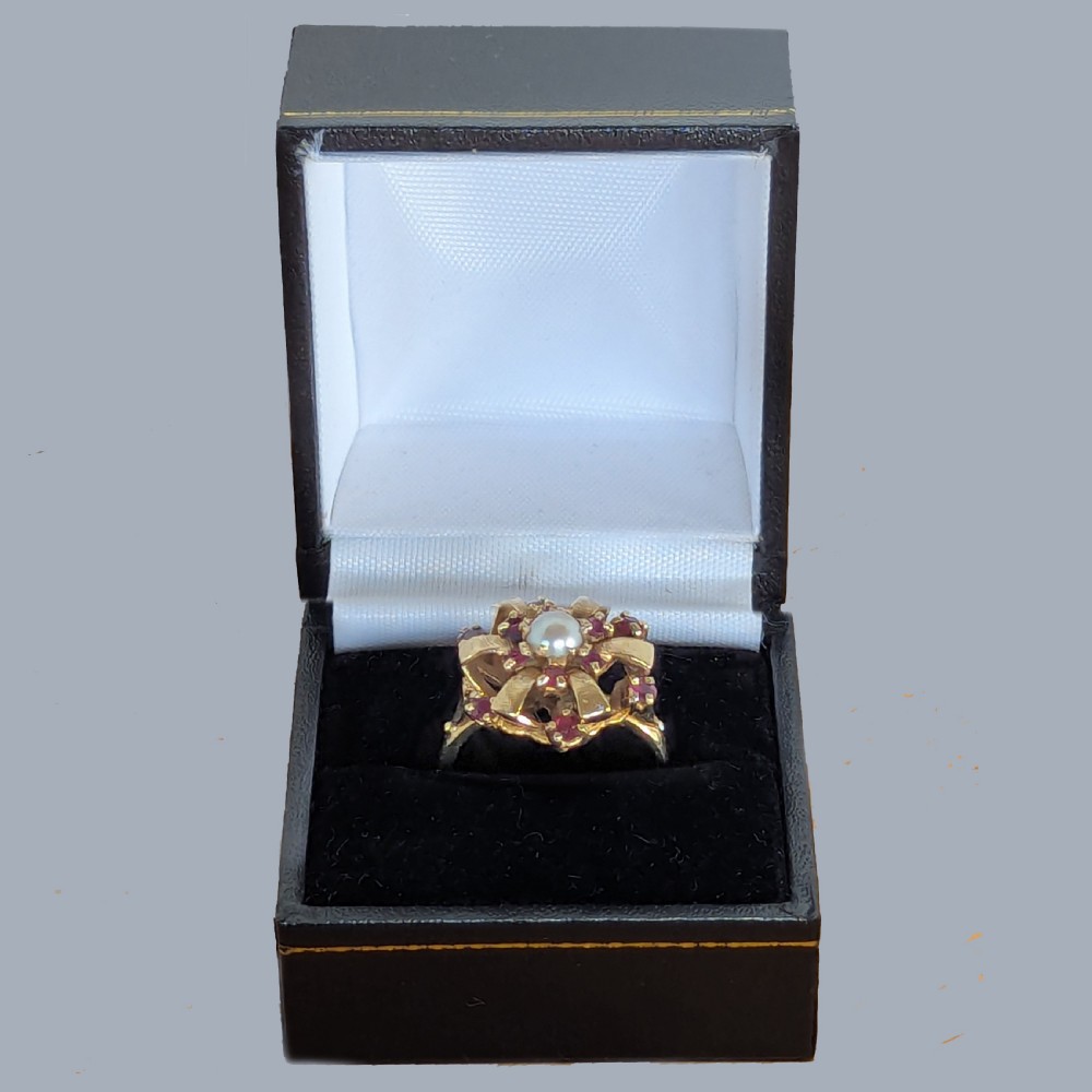 A 9ct yellow gold cluster ring featuring a central white pearl surrounded by textured gold ribbon loops set with round red rubies. View VII