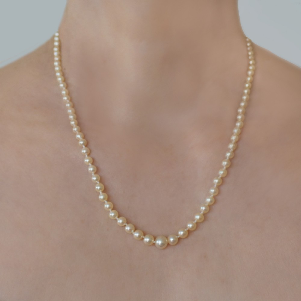 A single strand of graduated cream pearls featuring a fluted 18ct gold clasp and safety chain against a grey background. View II