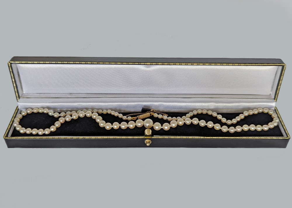 A single strand of graduated cream pearls featuring a fluted 18ct gold clasp and safety chain against a grey background. View VIII