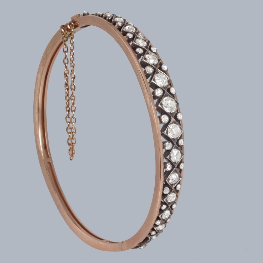 A Victorian 15ct gold and silver-topped hinged bangle set with a row of old mine cut diamonds in diamond-shaped mounts. View II