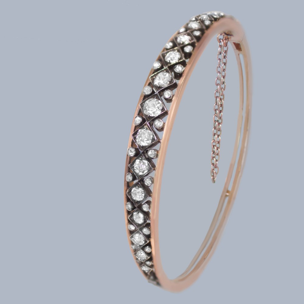 A Victorian 15ct gold and silver-topped hinged bangle set with a row of old mine cut diamonds in diamond-shaped mounts. View IV