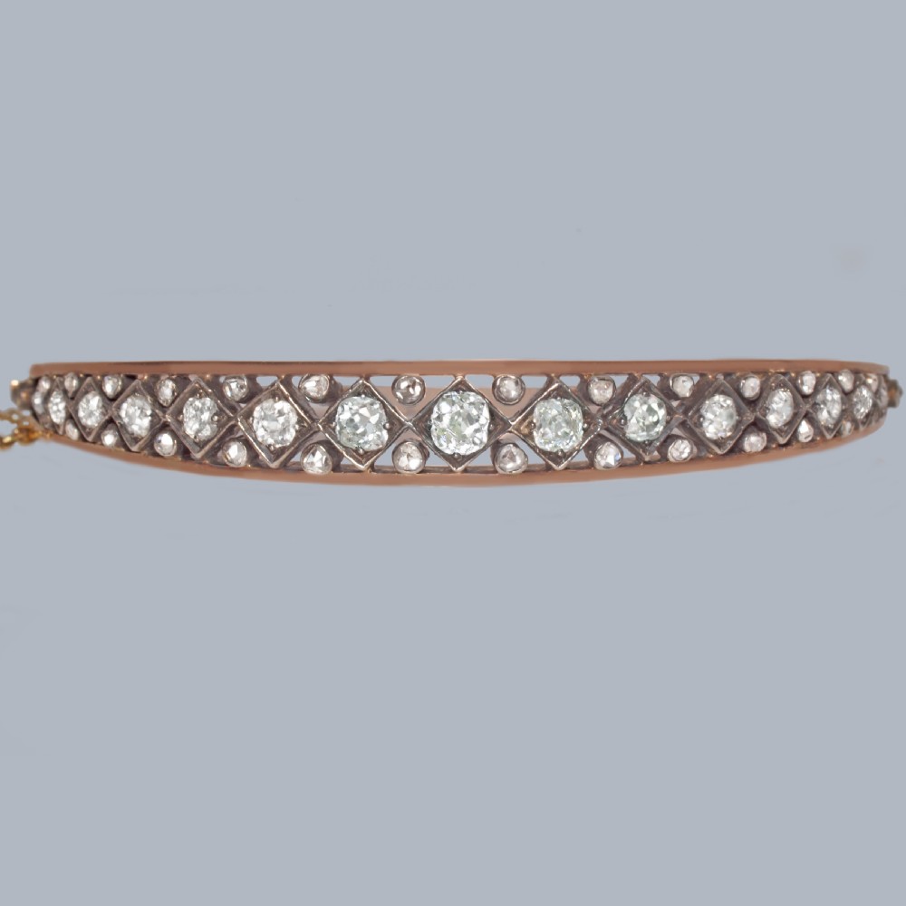 A Victorian 15ct gold and silver-topped hinged bangle set with a row of old mine cut diamonds in diamond-shaped mounts. View V