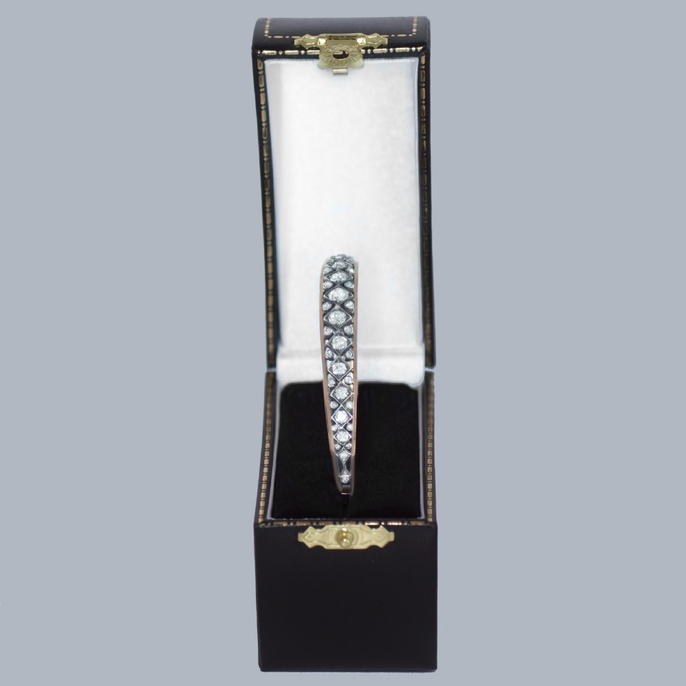 A Victorian 15ct gold and silver-topped hinged bangle set with a row of old mine cut diamonds in diamond-shaped mounts. View VI
