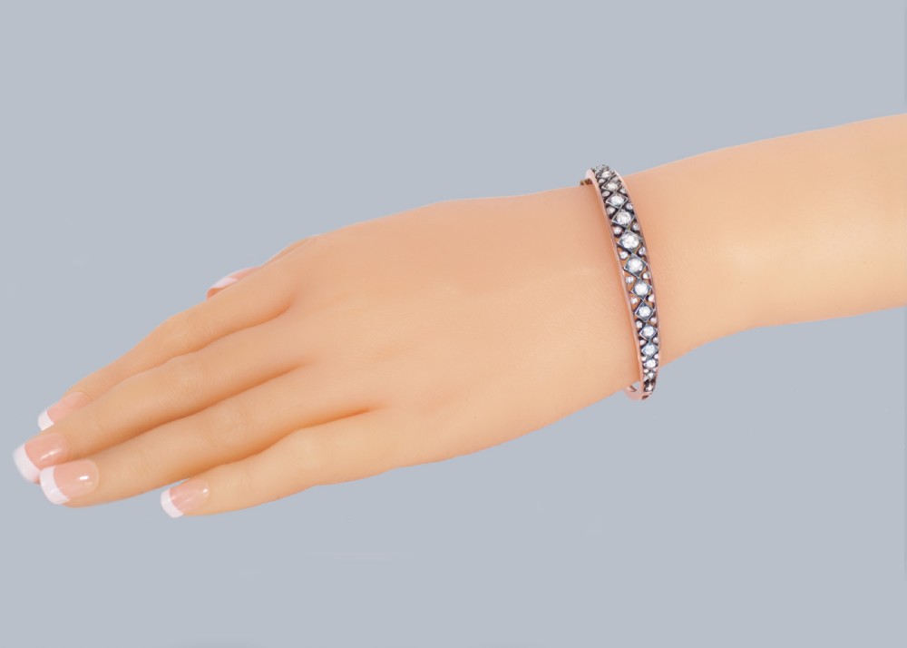 A Victorian 15ct gold and silver-topped hinged bangle set with a row of old mine cut diamonds in diamond-shaped mounts. View VIII