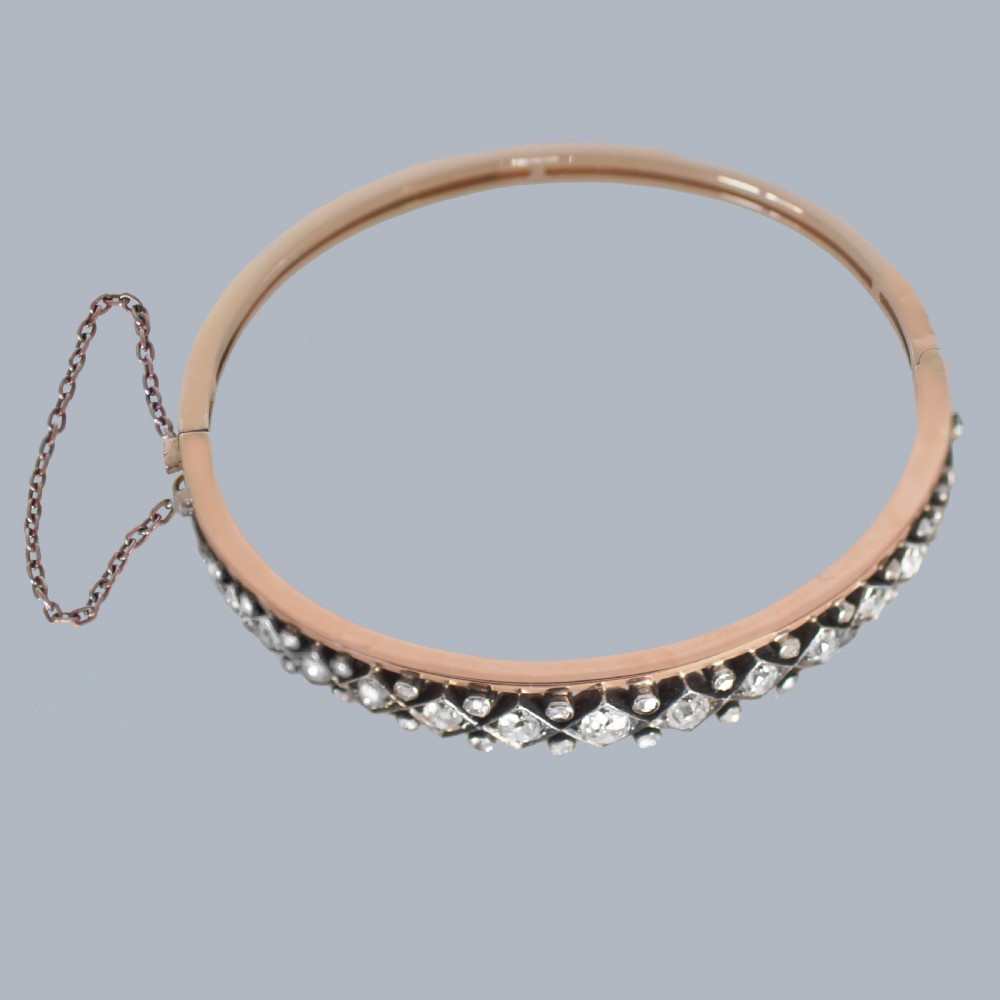 A Victorian 15ct gold and silver-topped hinged bangle set with a row of old mine cut diamonds in diamond-shaped mounts. View IX