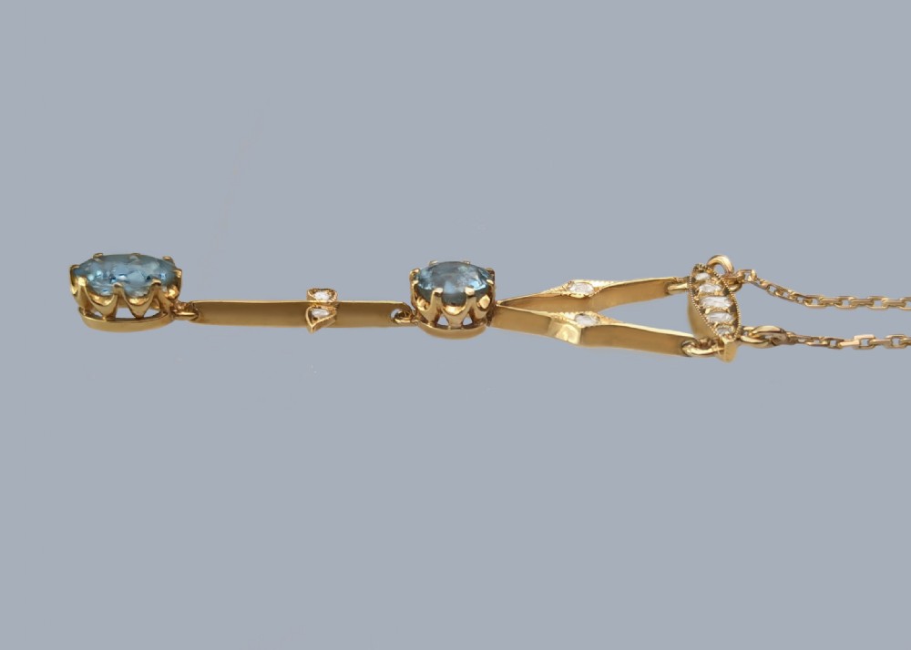 An Edwardian 9ct yellow gold lavalier drop necklace featuring two faceted light blue aquamarines suspended from an openwork bar set with accent diamonds. View III