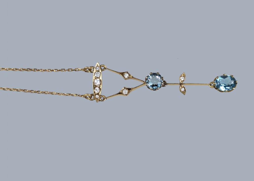 An Edwardian 9ct yellow gold lavalier drop necklace featuring two faceted light blue aquamarines suspended from an openwork bar set with accent diamonds. View IV