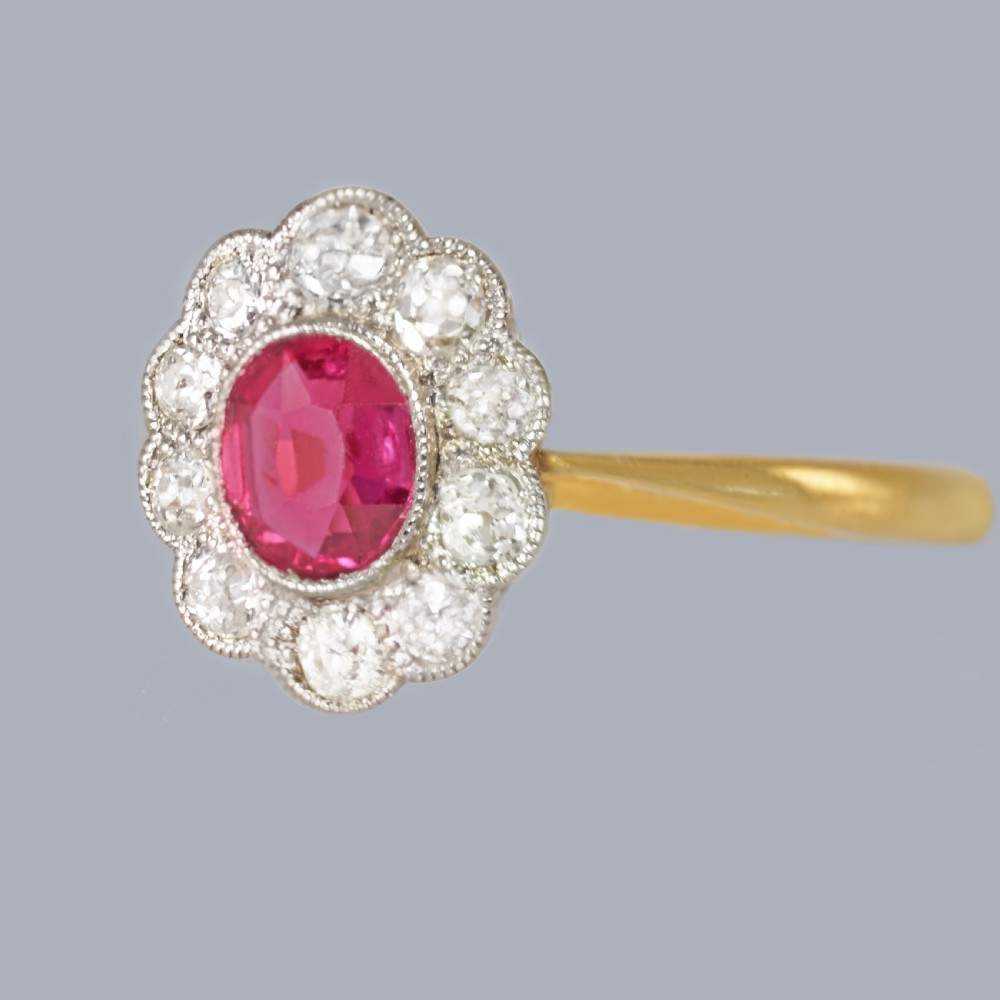 A vintage cluster ring featuring a central oval red ruby surrounded by ten round diamonds set in platinum with an 18ct yellow gold band. View VIII