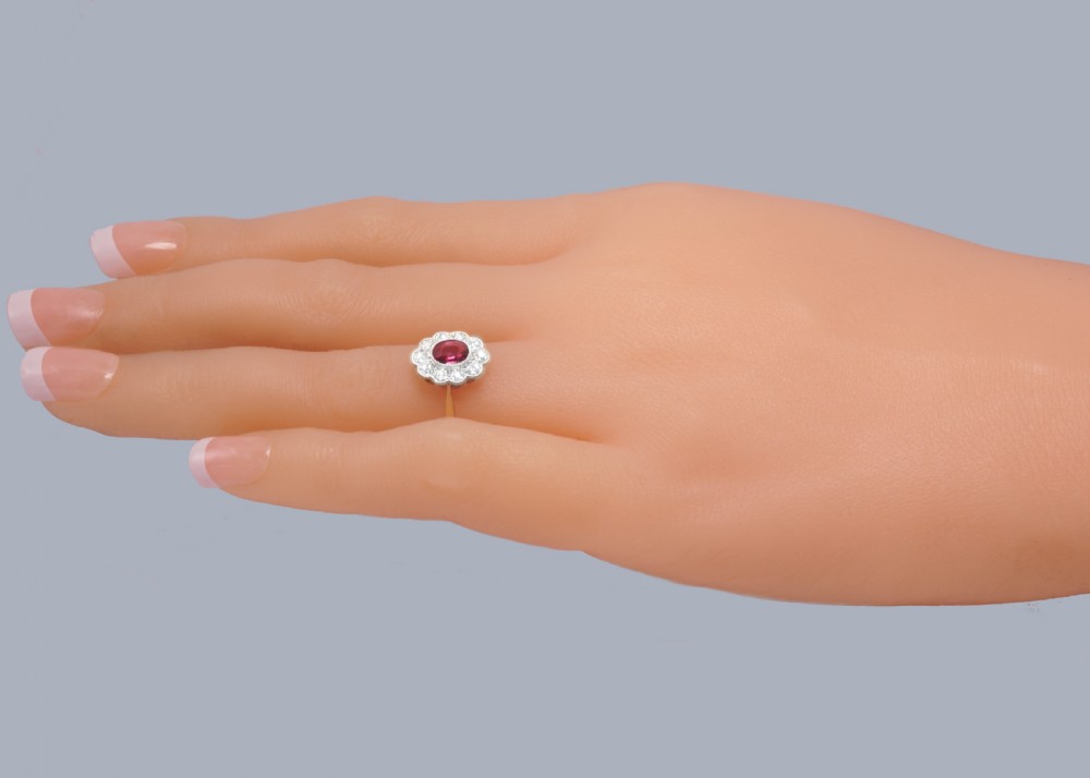 A vintage cluster ring featuring a central oval red ruby surrounded by ten round diamonds set in platinum with an 18ct yellow gold band. View XIII