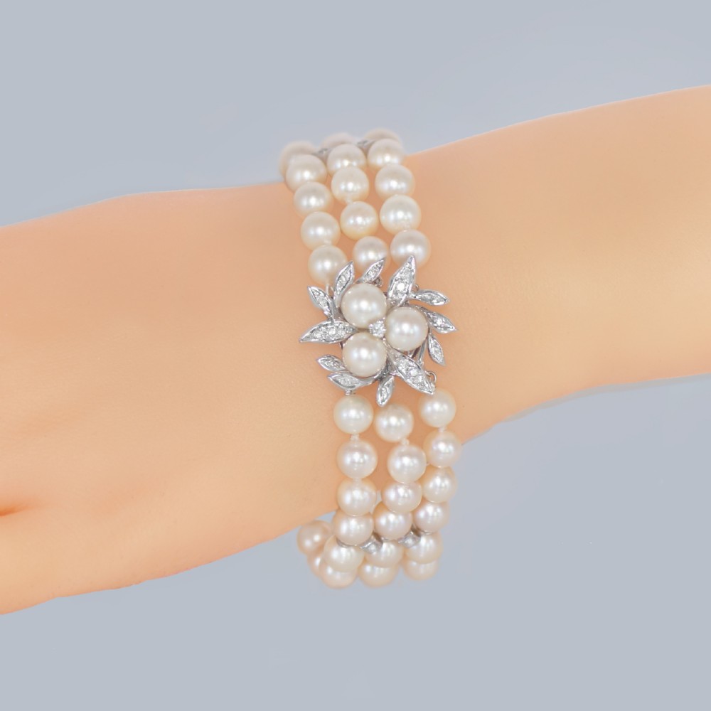 A vintage triple strand cultured pearl bracelet featuring a white gold floral clasp set with small diamonds and central pearls. View II