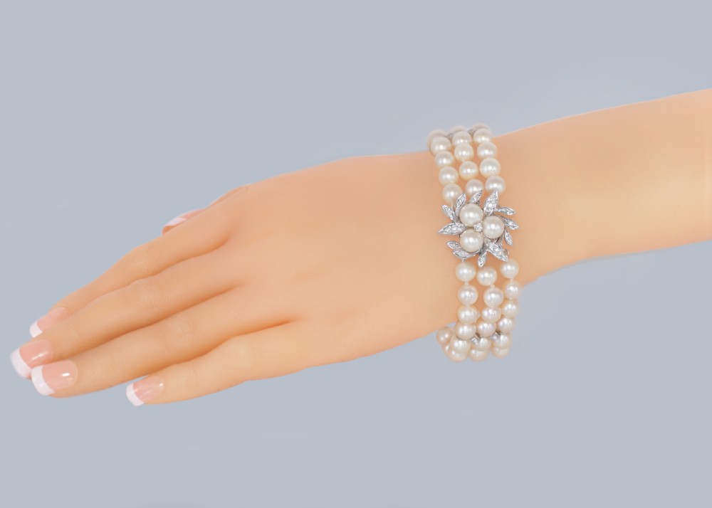 A vintage triple strand cultured pearl bracelet featuring a white gold floral clasp set with small diamonds and central pearls. View VII