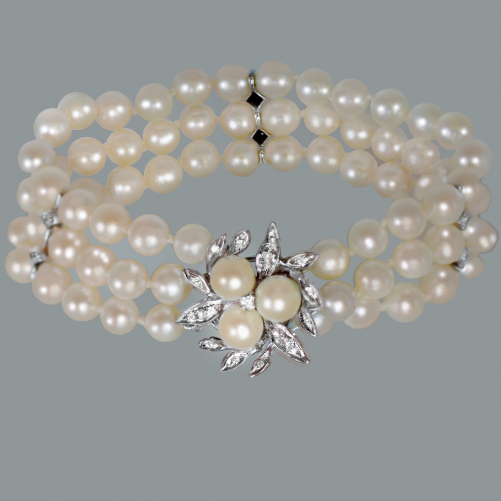 A vintage triple strand cultured pearl bracelet featuring a white gold floral clasp set with small diamonds and central pearls. View III