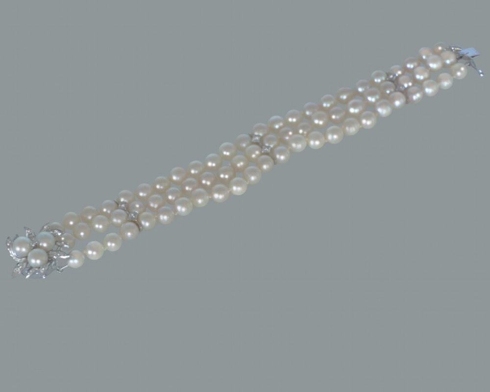 A vintage triple strand cultured pearl bracelet featuring a white gold floral clasp set with small diamonds and central pearls. View IV
