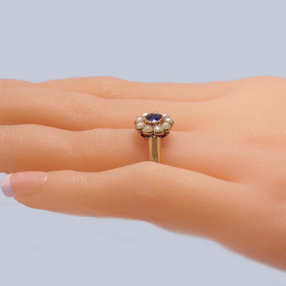An 18ct yellow gold Victorian cluster ring featuring a central round blue sapphire encircled by eight split pearls. View II