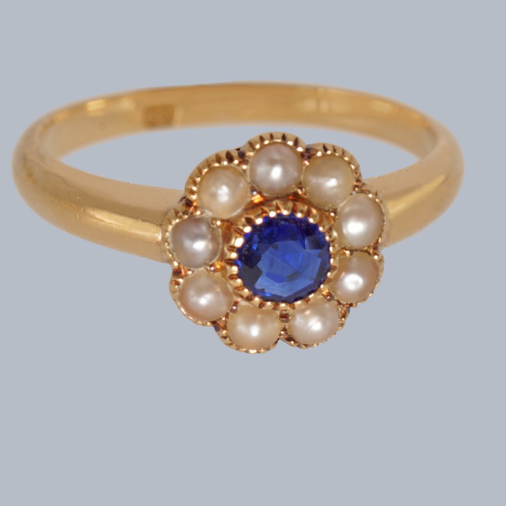 An 18ct yellow gold Victorian cluster ring featuring a central round blue sapphire encircled by eight split pearls. View III
