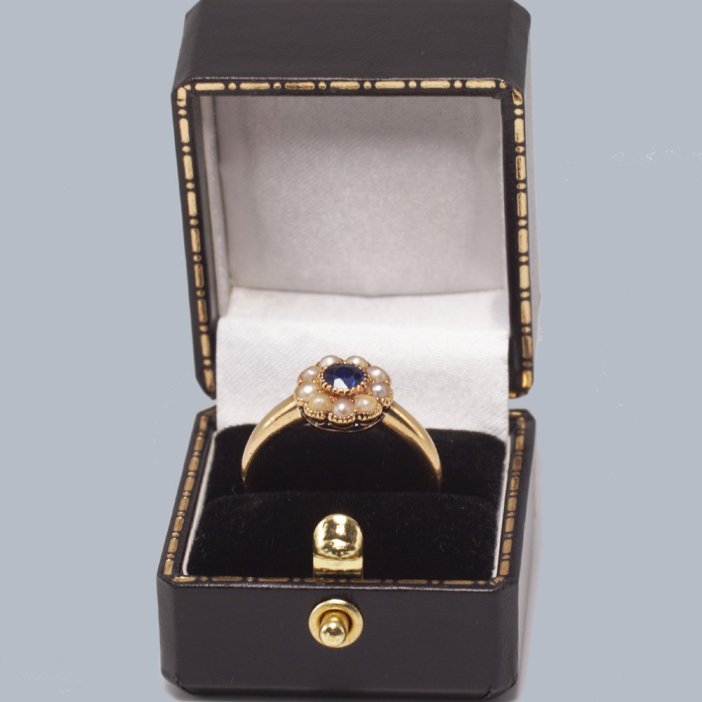 An 18ct yellow gold Victorian cluster ring featuring a central round blue sapphire encircled by eight split pearls. View IX
