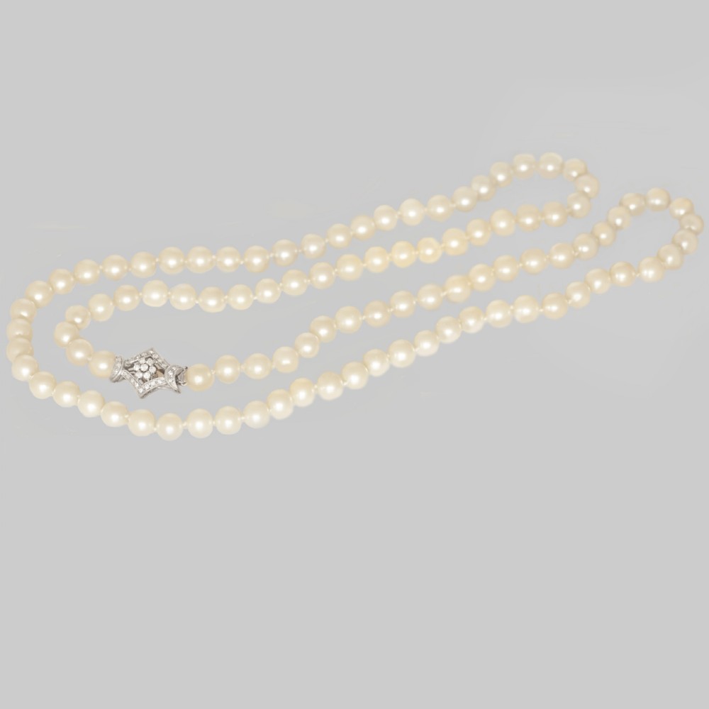 A long single strand of cream-coloured pearls fitted with a geometric 18ct white gold clasp set with diamonds.