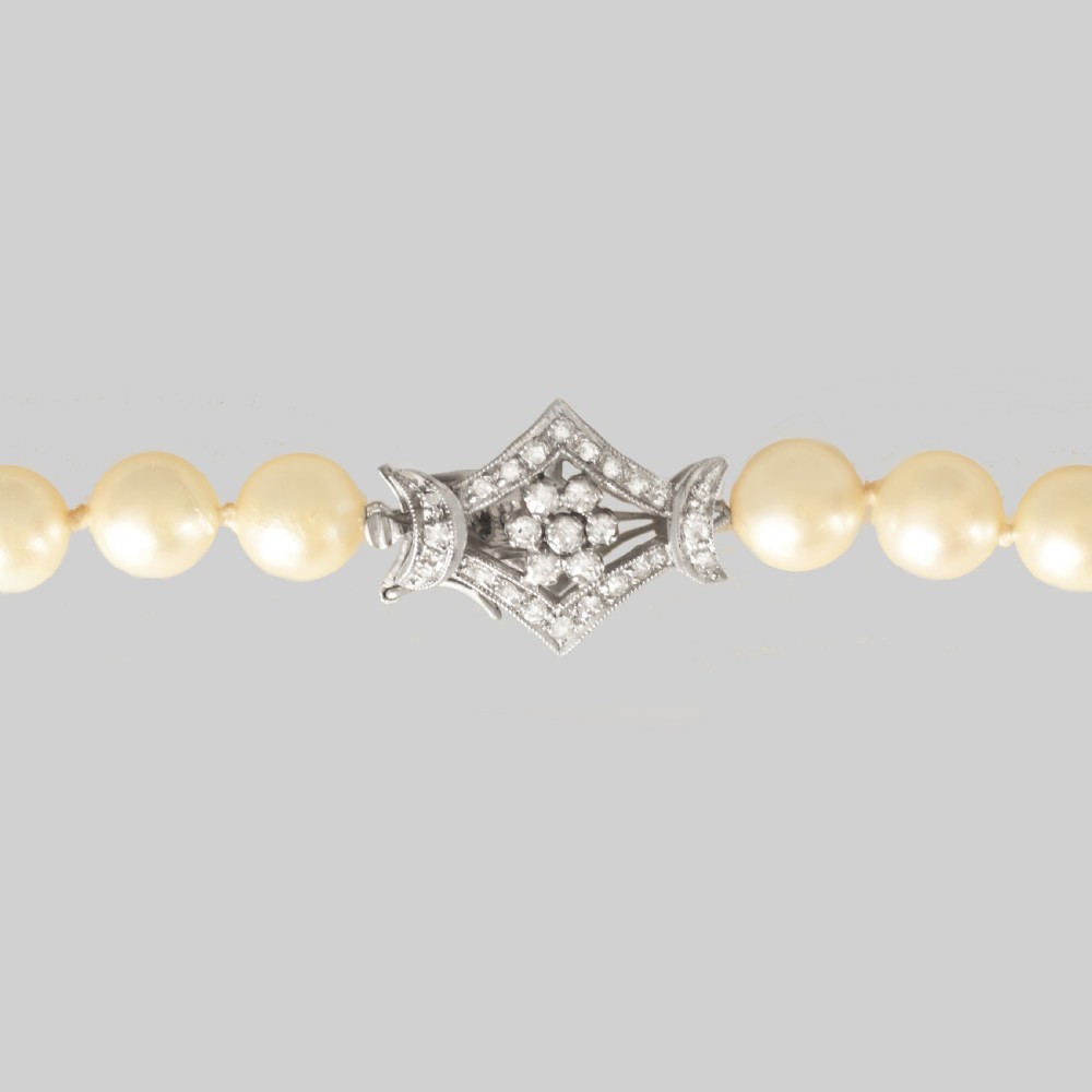 A long single strand of cream-coloured pearls fitted with a geometric 18ct white gold clasp set with diamonds. View II