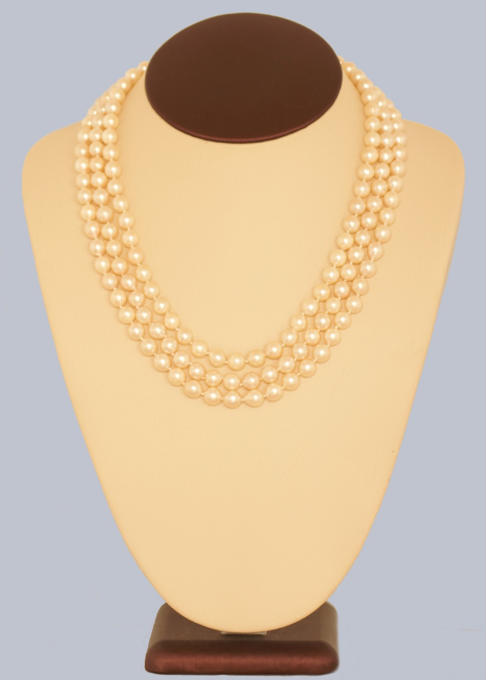 A 1960s triple strand cultured pearl necklace featuring cream-coloured pearls and a 9ct gold floral cluster clasp. View III
