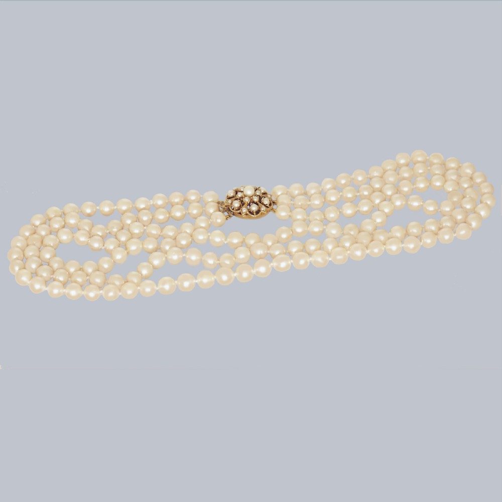 A 1960s triple strand cultured pearl necklace featuring cream-coloured pearls and a 9ct gold floral cluster clasp. View VIII