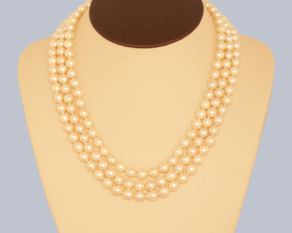A 1960s triple strand cultured pearl necklace featuring cream-coloured pearls and a 9ct gold floral cluster clasp. View XIII