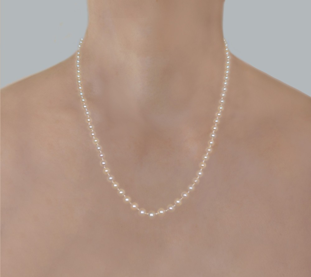 A single strand of cream pearls resting against skin, fastened around the neckline.
