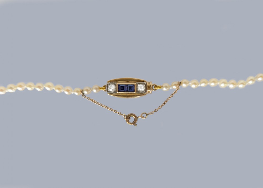 A single strand of cream pearls resting against skin, fastened around the neckline. View IV