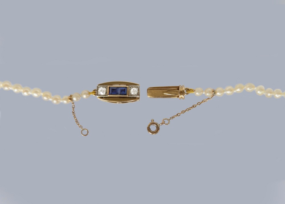 A single strand of cream pearls resting against skin, fastened around the neckline. View V