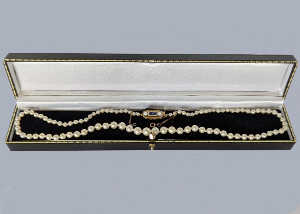 A single strand of cream pearls resting against skin, fastened around the neckline. View VII