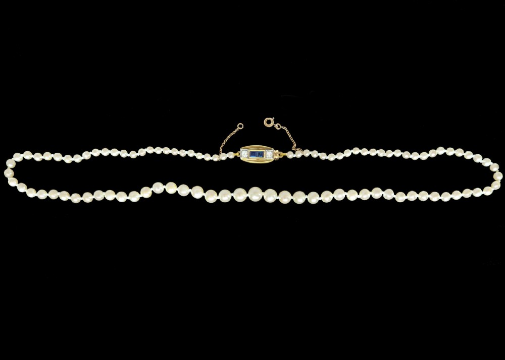 A single strand of cream pearls resting against skin, fastened around the neckline. View VIII