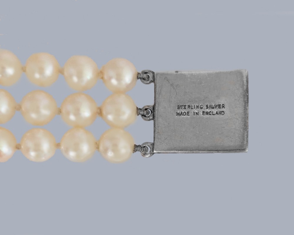 A triple strand cultured pearl bracelet featuring a rectangular sterling silver clasp decorated with marcasite stones and a central pearl. View VI