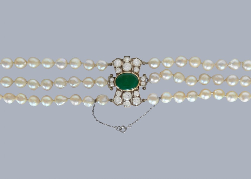 A 1920s triple strand pearl necklace featuring an Art Deco geometric clasp set with an oval green jadeite cabochon. View IX