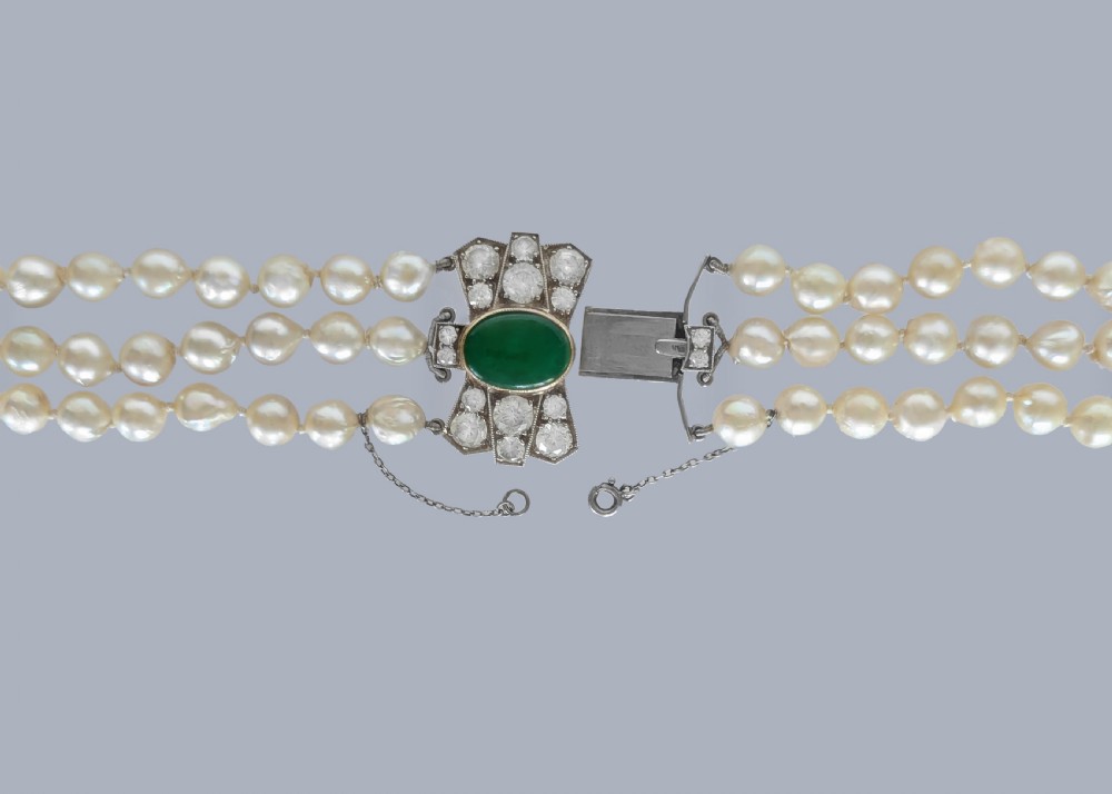 A 1920s triple strand pearl necklace featuring an Art Deco geometric clasp set with an oval green jadeite cabochon. View X