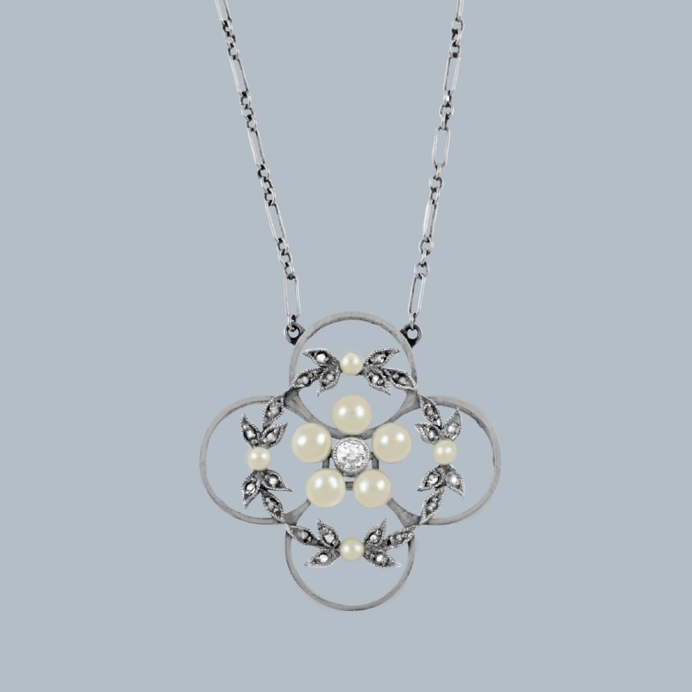 An Edwardian openwork platinum pendant featuring a central diamond encircled by pearls and leaf motifs, suspended on a fine platinum chain.