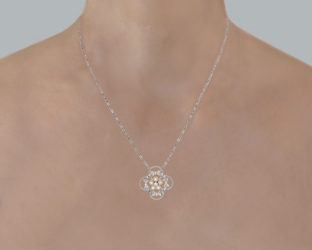 An Edwardian openwork platinum pendant featuring a central diamond encircled by pearls and leaf motifs, suspended on a fine platinum chain. View VIII