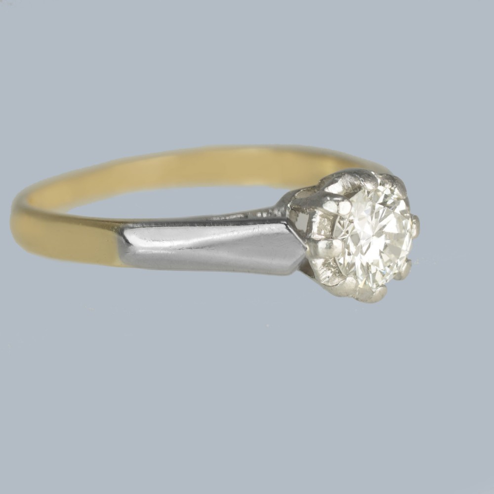An Art Deco diamond solitaire ring featuring a round central diamond held in a platinum setting on an 18ct yellow gold band. View IV