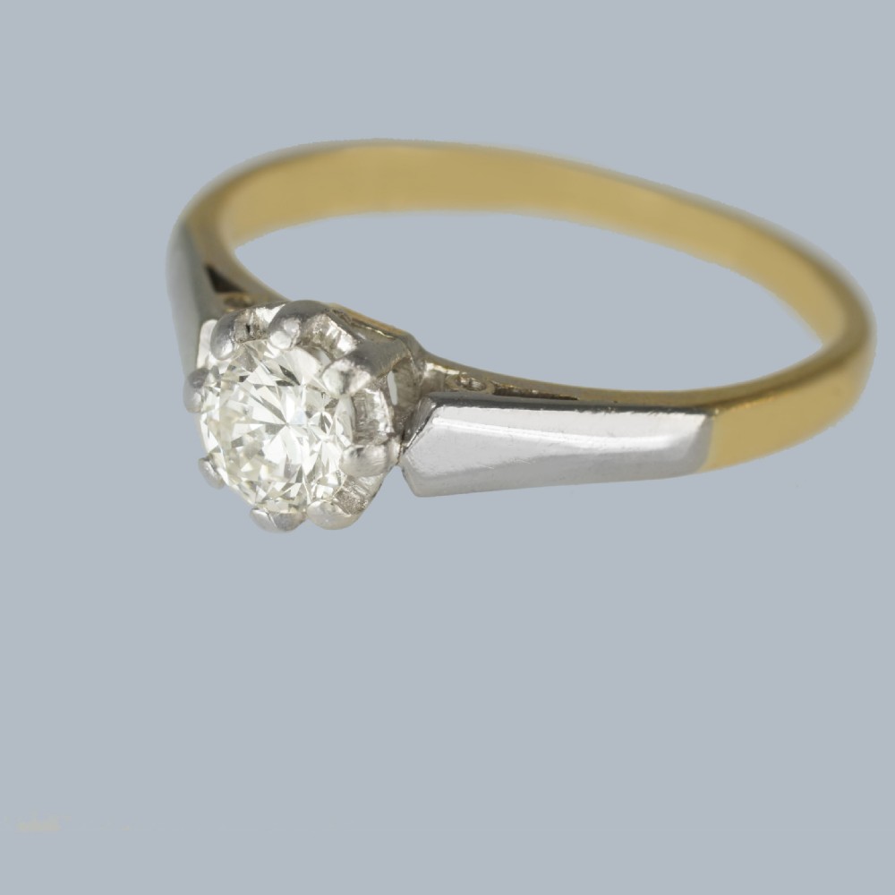 An Art Deco diamond solitaire ring featuring a round central diamond held in a platinum setting on an 18ct yellow gold band. View V