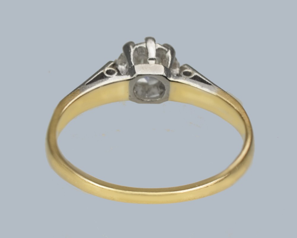 An Art Deco diamond solitaire ring featuring a round central diamond held in a platinum setting on an 18ct yellow gold band. View VII