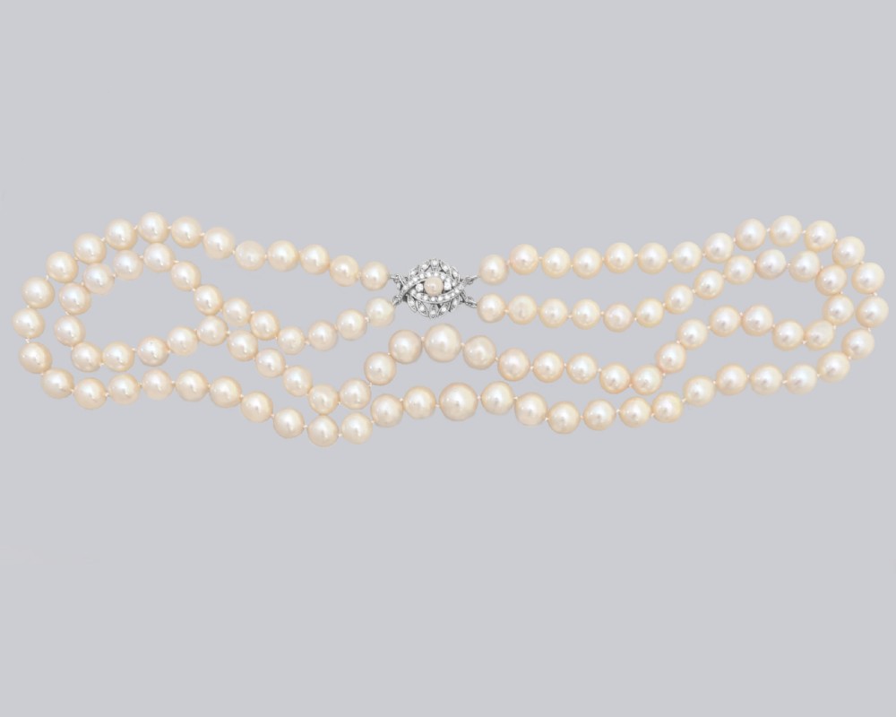 A vintage double strand cream pearl necklace featuring an ornate 9ct white gold foliate clasp set with small diamonds. View IV