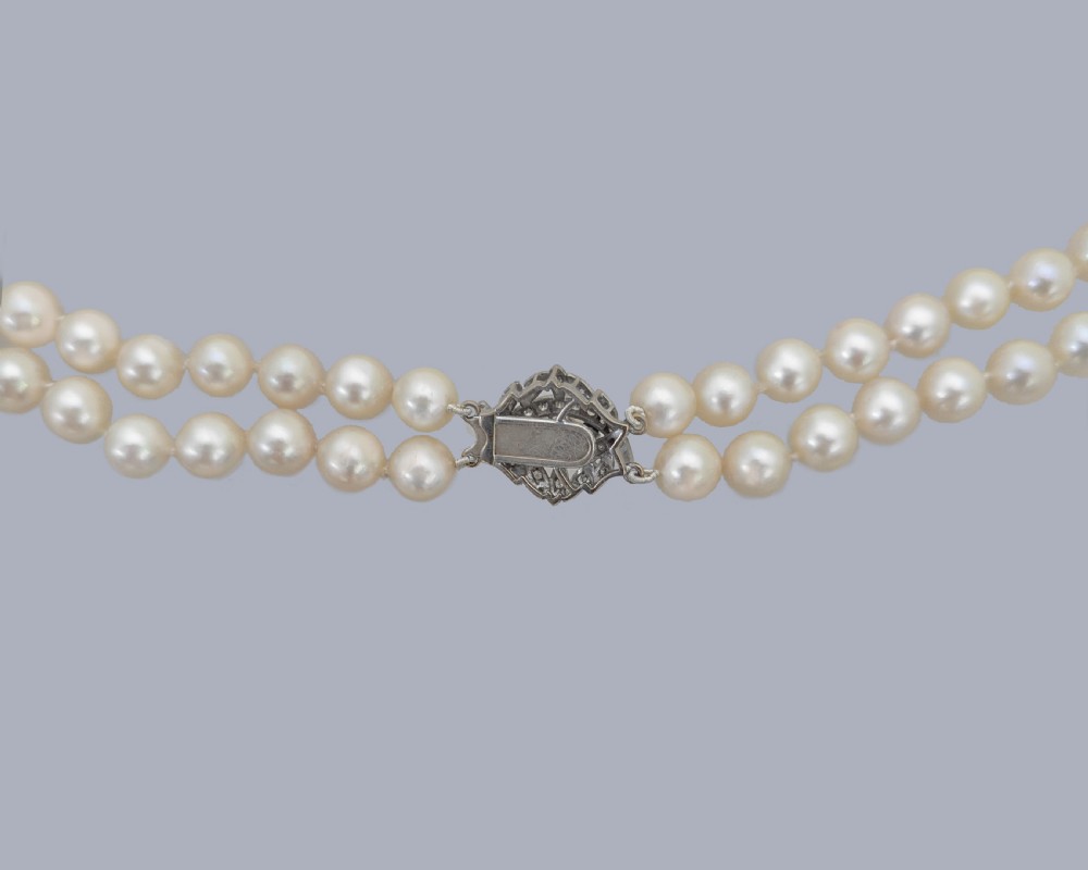 A vintage double strand cream pearl necklace featuring an ornate 9ct white gold foliate clasp set with small diamonds. View VII