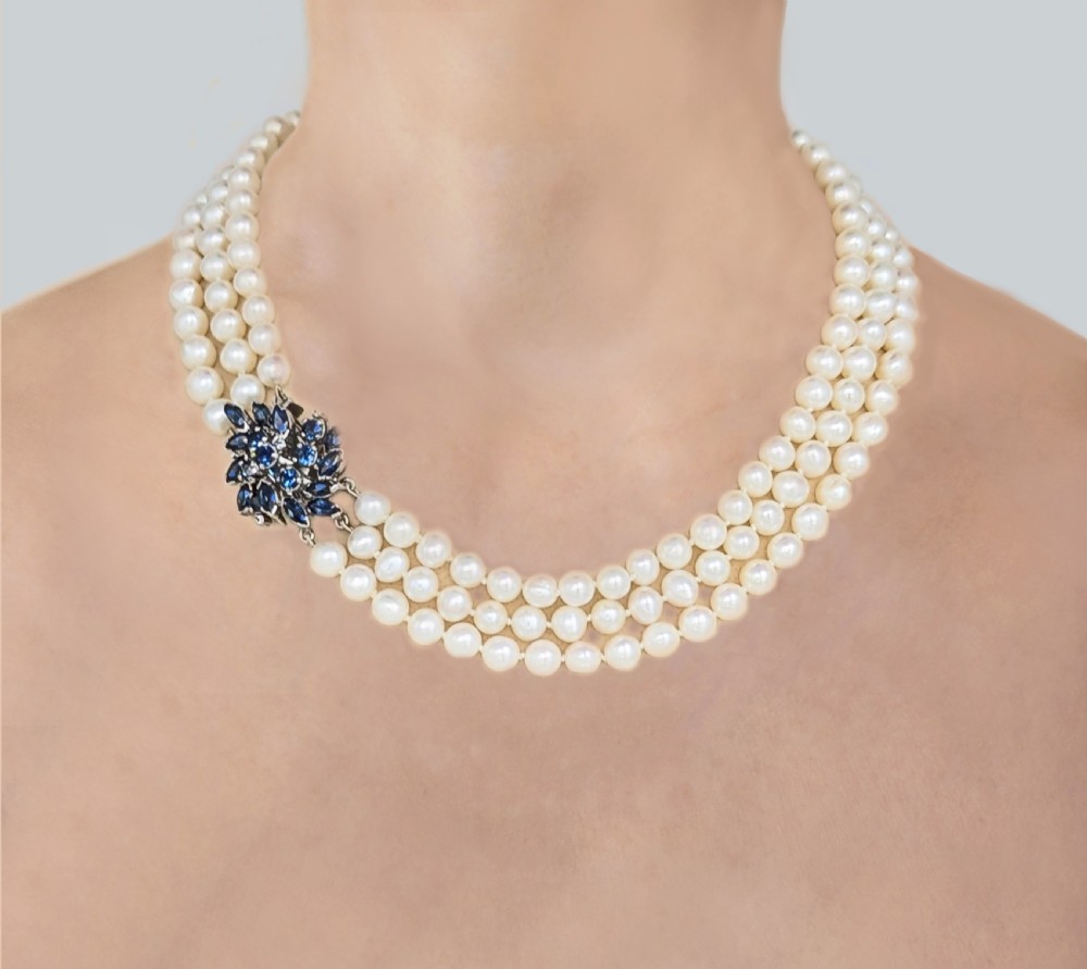 A vintage three-strand white pearl necklace joined by a silver floral clasp set with marquise-cut blue sapphires and small diamonds. View XVI