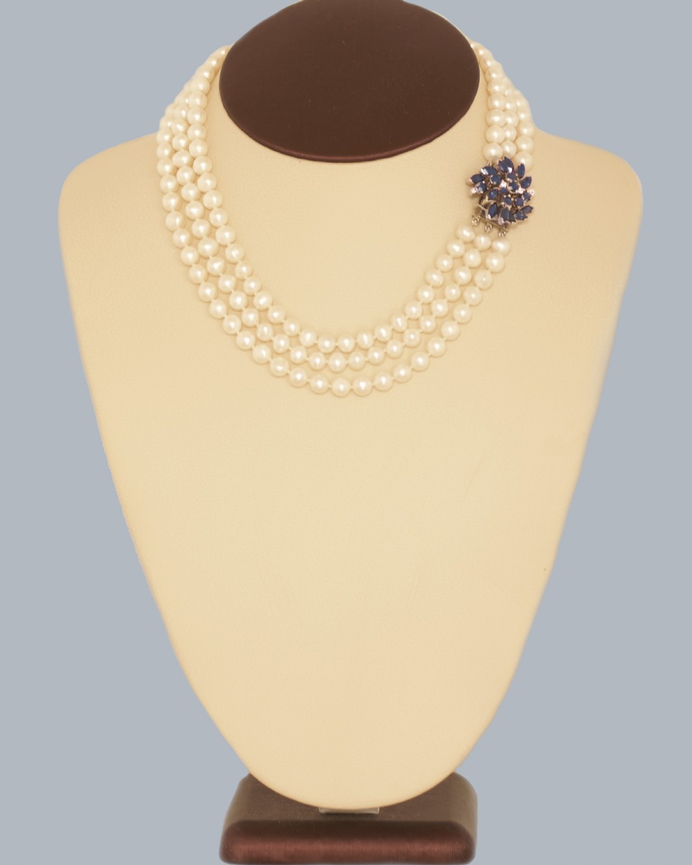 A vintage three-strand white pearl necklace joined by a silver floral clasp set with marquise-cut blue sapphires and small diamonds. View XVII