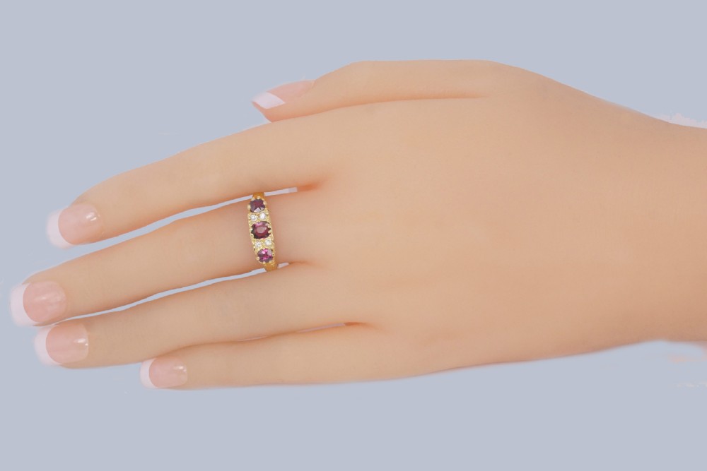 A Late Victorian 18ct yellow gold carved gallery ring set with three oval rubies and four small old cut diamonds. View VII