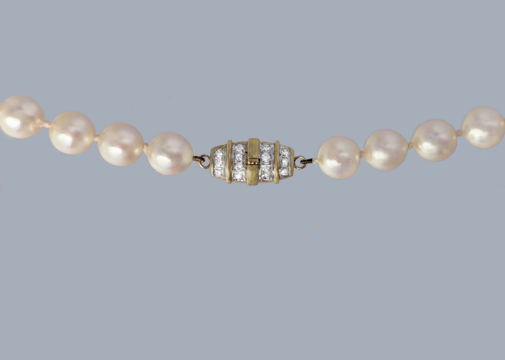A single strand of uniform cultured cream pearls featuring an ornate 9ct gold clasp embellished with diamonds. View VI