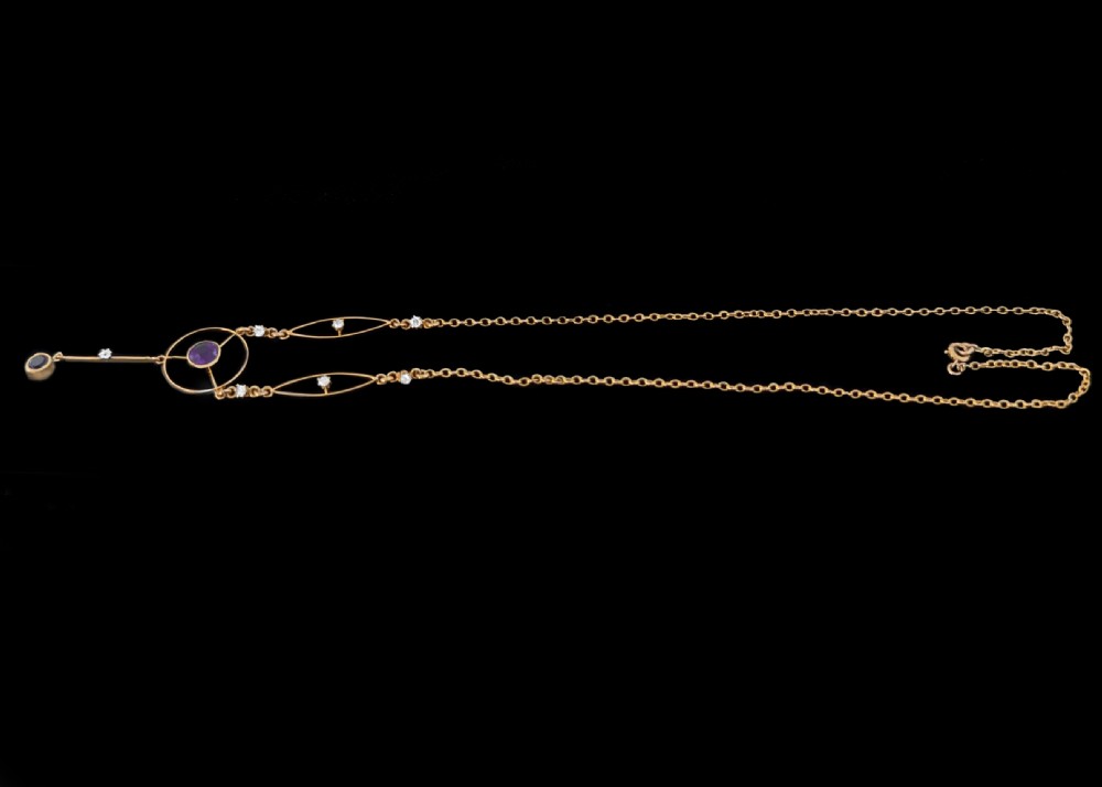 An Edwardian 18ct gold lavalier necklace featuring openwork geometric wire loops set with small diamonds, a central round bezel-set amethyst, and a vertical drop terminating in a second amethyst stone. View V