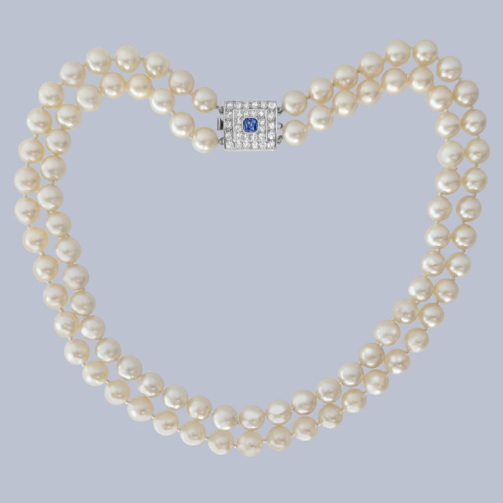 A double strand cream pearl necklace featuring a square 18ct white gold clasp set with a central square blue sapphire and accent diamonds.